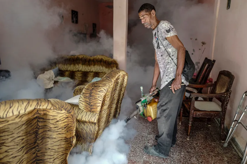 Un employé du ministère cubain de la Santé pulvérise des produits anti-moustiques dans une habitation du quartier de Jesus María, à La Havane, le 20 novembre 2025 © ADALBERTO ROQUE / AFP